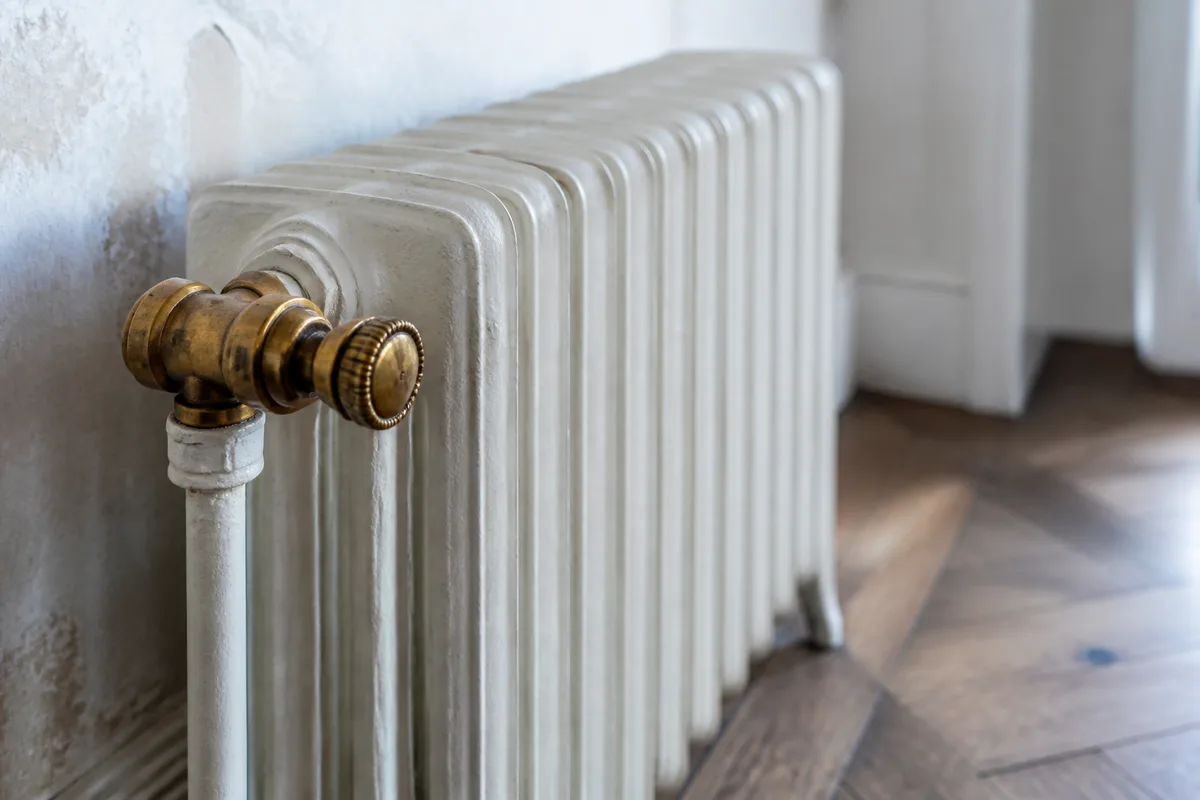 Radiateur en fonte ancien et robinet thermostatique en laiton dans un logement ancien
