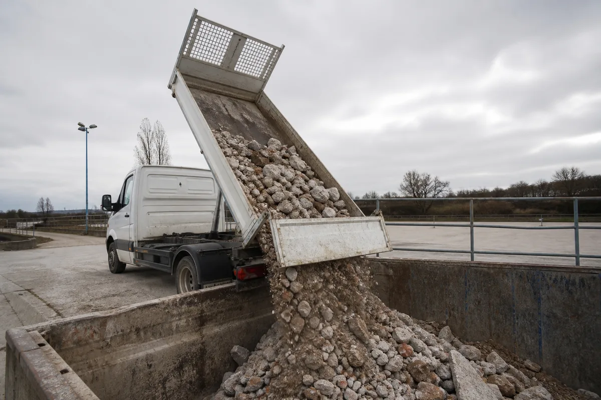 Benne d&rsquo;utilitaire basculée déversant des gravats sur une plateforme de déchèterie